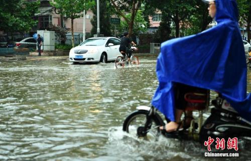 7月16日，河北石家莊一條馬路積水嚴(yán)重，民眾涉水騎行。當(dāng)日，該省氣象臺(tái)發(fā)布暴雨藍(lán)色預(yù)警，多地遭受暴雨襲擊。<a target='_blank' >中新社</a>記者 翟羽佳 攝
