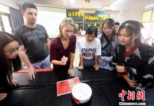 圖為外籍教師在體驗(yàn)“博餅”游戲?！埍蟆z