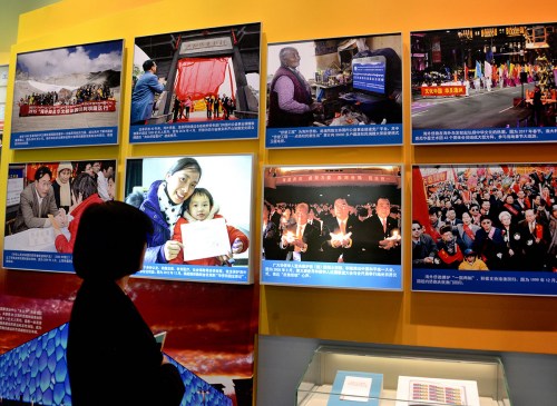 一位參觀者在“海外僑胞心系祖國 助力改革開放”展廳，觀看“2005年5月，第三屆世界華僑華人社團聯(lián)誼大會與會代表舉行燭光祈愿儀式，表達‘反獨促統(tǒng)’心聲”等展覽照片。（《芝加哥華語論壇》/張大衛(wèi) 攝）
