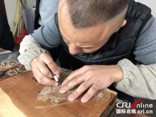皮影匠人用華州皮影獨一無二的“推皮走刀法”雕刻。攝影：張捷