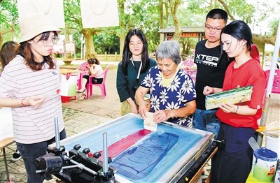 嘉年華活動(dòng)設(shè)計(jì)和絲印組成員手把手教村民制作絲印作品。 海南日報(bào)記者 蘇曉杰 通訊員 王家專 攝