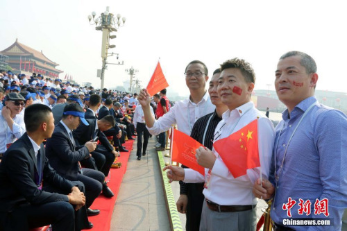 10月1日，慶祝中華人民共和國(guó)成立70周年大會(huì)在北京隆重舉行。約2000名海外華僑華人在現(xiàn)場(chǎng)見證了歷史時(shí)刻。他們表示，國(guó)慶慶典展現(xiàn)了中華民族的自信和威嚴(yán)，凝聚起了全球僑胞的心。圖為來自巴布亞新幾內(nèi)亞的薛輝雄等在觀禮臺(tái)合影。<a target='_blank' >中新社</a>記者 任海霞 攝