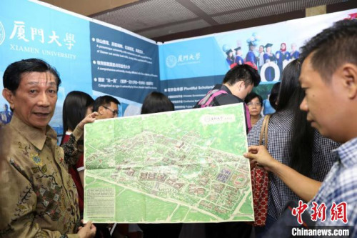 圖為廈門大學參展人員向咨詢者展現(xiàn)“中國最美校園”地圖?！×钟纻?攝