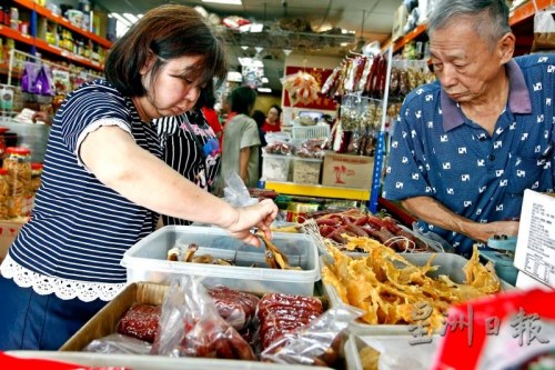 在店員的幫助下，民眾仔細挑選臘鴨腿。(《星洲日報》/蔡偉傳 攝)