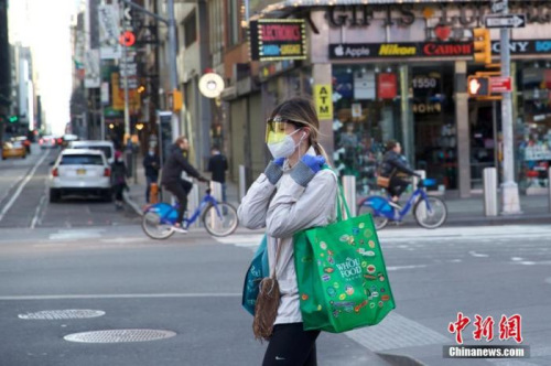 當?shù)貢r間3月21日，美國紐約時代廣場一位行人防護嚴密。<a target='_blank' >中新社</a>記者 廖攀 攝