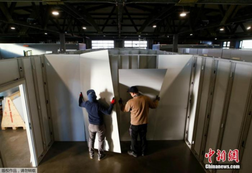 當(dāng)?shù)貢r(shí)間3月25日，德國希勒斯海姆，工作人員和志愿者將市政大廳改建為醫(yī)療中心用于收治新型冠狀病毒患者。圖為工作人員和志愿者在安裝醫(yī)療中心隔間的墻面。