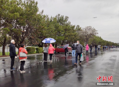 美國舊金山灣區(qū)民眾在位于福斯特城的Costco超市外冒雨排起長隊，等候購買物資。<a target='_blank' >中新社</a>記者 劉關(guān)關(guān) 攝