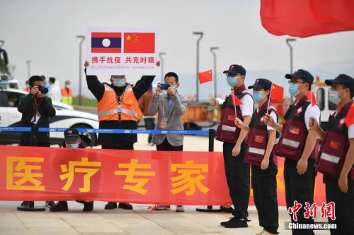 抗疫醫(yī)療專家組一行12人順利完成工作任務，乘包機平安飛抵云南昆明。圖為機場工作人員手舉印有中老兩國國旗的牌子迎接專家組。( <a target='_blank' >中新社</a>記者 劉冉陽 攝)