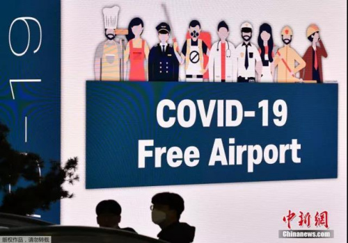 位于韓國首爾的仁川國際機場，戴著口罩的人們走過大屏幕。(<a target='_blank'  >中新網(wǎng)</a>)
