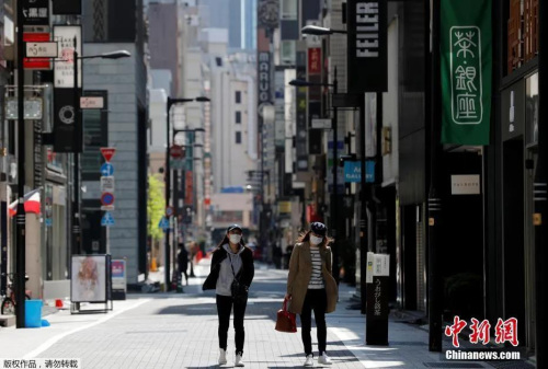 日本東京，戴口罩的女士走過(guò)空無(wú)一人的購(gòu)物區(qū)。