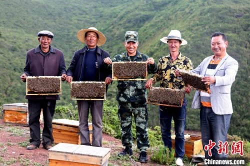 布哈與村民展示養(yǎng)蜂成果。圖片由武警部隊提供