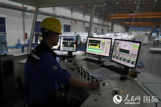 鼎力新材料公司的工廠投資1.2億美元，每年可以生產(chǎn)規(guī)格從5mic—2mm的鋁箔共計(jì)8萬噸。圖為技術(shù)員在操作切割鋁箔的軋機(jī)。人民網(wǎng)記者孫廣勇攝