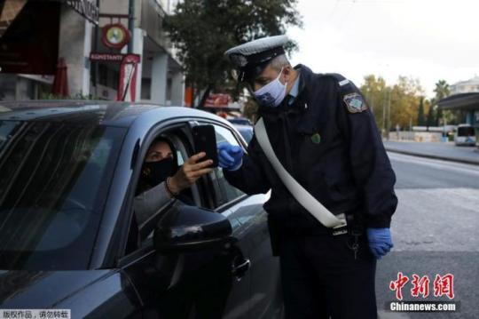 當(dāng)?shù)貢r間11月7日，希臘雅典，一名警察正在檢查司機證件，確定其出行目的。為遏制新冠疫情，自當(dāng)?shù)貢r間7日早晨6時起，希臘全國進(jìn)入為期三周的封鎖狀態(tài)。新的限制措施將禁止區(qū)域間的旅行。