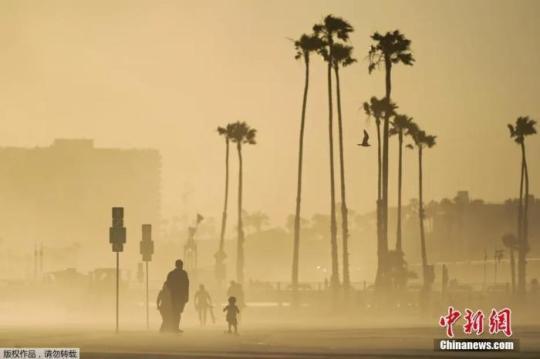 當(dāng)?shù)貢r間4月18日，美國加州海邊大風(fēng)卷起沙土，游客在漫天黃沙中出行。