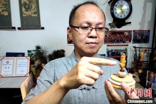 圖為黃樹立與核雕“火炬”作品。　梅鐿瀧 攝