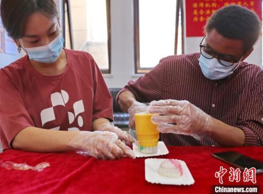 圖為社區(qū)居民和外國(guó)留學(xué)生一起制作月餅?！〔芙ㄐ?攝