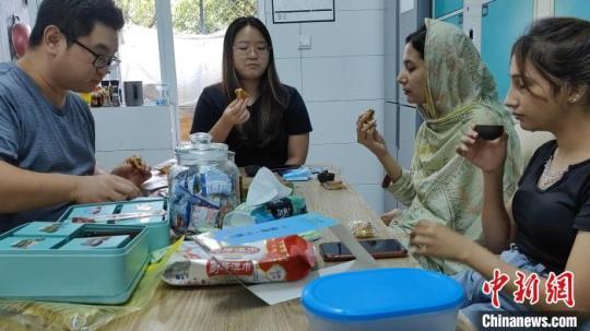 謝志功和外籍學(xué)生品嘗月餅、喝茶聊天?！∈茉L者供圖