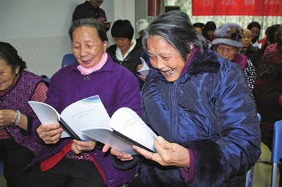 中國僑網(wǎng)大鵬新區(qū)居民開心翻看僑法宣傳手冊(cè)。(《深圳僑報(bào)》/林琳 攝)