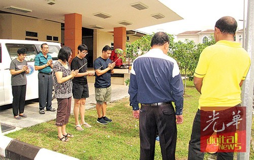 死于心臟病爆發(fā)年邁夫婦的3名子女及親友于醫(yī)院太平間,持香隨道士念經(jīng)作法。(馬來西亞《光華日報》)