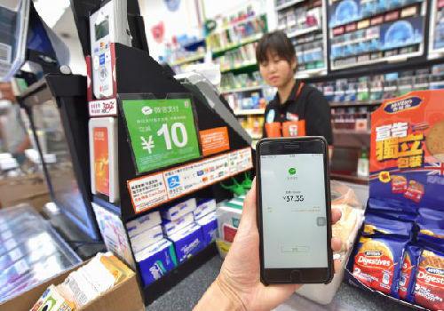 中國(guó)僑網(wǎng)資料圖:一名顧客在香港7-Eleven便利店體驗(yàn)使用微信支付并獲得優(yōu)惠。(新華社)