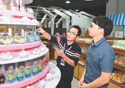 中國僑網(wǎng)臺灣青年創(chuàng)業(yè)者曾翊展(左)在廈門“寶島夢工廠”里指導(dǎo)員工擺設(shè)商品。 新華社記者 姜克紅攝