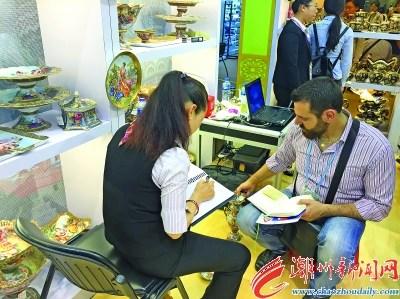 中國僑網(wǎng)圖為潮州市參展企業(yè)營銷人員與國外采購商開展訂單洽談。 本報(bào)記者 曾曉純 楊燕芳 攝