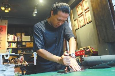 中國(guó)僑網(wǎng)何巍正在給皮具原料裁邊。