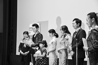中國僑網(wǎng)圖為《洋妞到我家》導(dǎo)演陳剛(右二)和小演員陳一諾在放映儀式上接受觀眾獻(xiàn)花。(謝宗睿 攝)