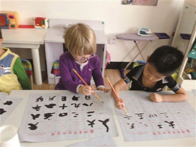 中國(guó)僑網(wǎng)斯汀的孩子(左一)學(xué)寫漢字。(王英 攝)