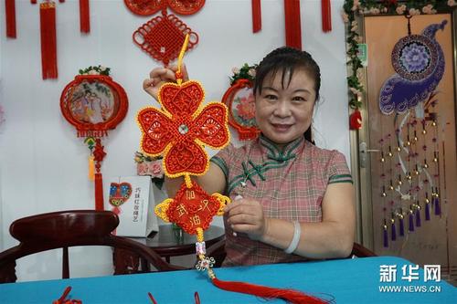 中國僑網(wǎng)5月21日,天津市河北區(qū)非物質(zhì)文化遺產(chǎn)項(xiàng)目“巧妹紅妝繩藝”代表性傳承人呂敏展示其創(chuàng)作的作品。(新華社/栗雅婷 攝)